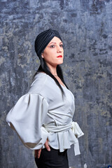 In a dark room stands a beautiful girl with long hair, dressed in a black leather skirt and a white blouse. Her outfit is designed in a business style. This is the image of a business woman.