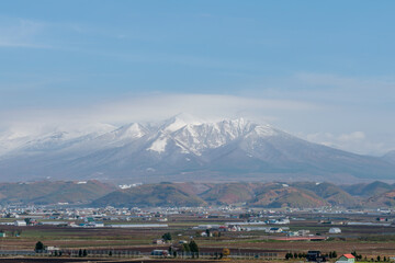 冠雪した十勝岳連峰と富良野の農村風景