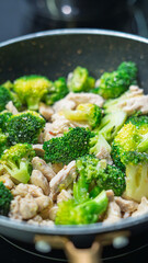 Ground meat and broccoli stir-frying in a non-stick pan. Mixed vegetables and protein cooking together on stovetop. Healthy homemade meal preparation concept with overhead view.