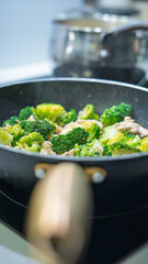 Ground meat and broccoli stir-frying in a non-stick pan. Mixed vegetables and protein cooking together on stovetop. Healthy homemade meal preparation concept with overhead view.