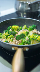 Ground meat and broccoli stir-frying in a non-stick pan. Mixed vegetables and protein cooking together on stovetop. Healthy homemade meal preparation concept with overhead view.