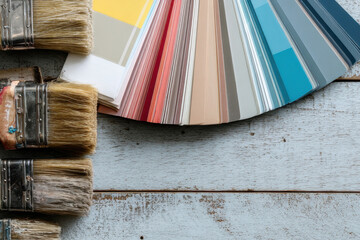home renovation tools and materials on wooden background, paint brushes, color swatches, hammer