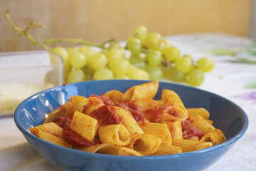 rigatoni pasta with fresh cherry tomato sauce in blue bowl on table