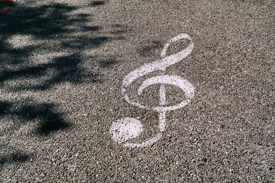 Clef de sol blanche dessin&eacute;e sur le sol. Symbole musical peint sur le goudron de la rue.