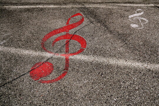 Clef de sol rouge dessin&eacute;e sur le sol. Symbole musical peint sur le goudron de la rue.