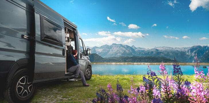 Frau mit ihrem Camper Van an einem Bergsee 