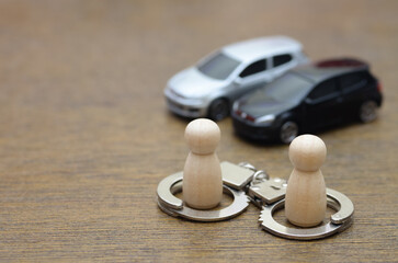 Detained for Car Theft: Two peg dolls stand in miniature handcuffs, representing the arrest of two...