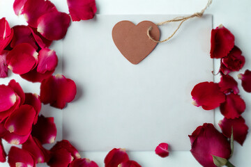 Blank card surrounded by red rose petals and a heart tag