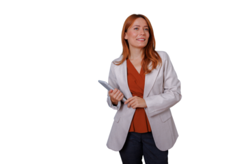 Businesswoman with red hair holding tablet, smiling and looking away, standing confidently on transparent background