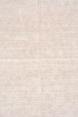 Fototapeta premium A detailed vertical close-up of a light beige, tightly woven textile surface with a visible fold lines and rough canvas-like texture, suitable for a minimalist background