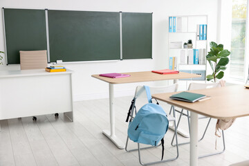 Green chalkboard and stylish furniture in classroom. Mockup for design
