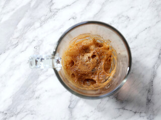 Top View of Espresso Coffee in a Glass Cup with Crema on a White Marble Surface