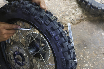 Close up of focused mechanic repairing motorcycle wheel in garage. person changing knobby tire with tool, performing bike maintenance and service for off road sport