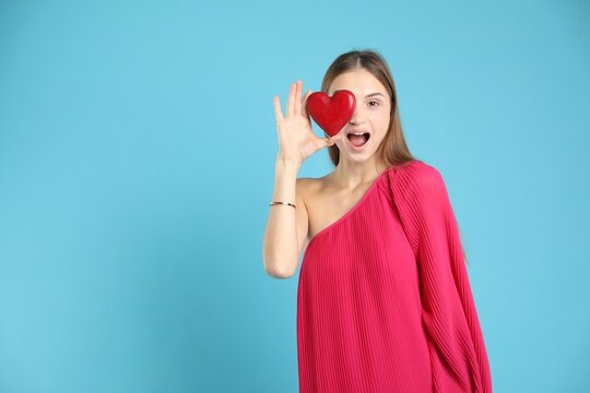 Emotional woman with heart figure on light blue background. Space for text