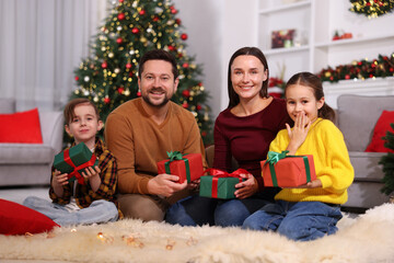 Happy family with Christmas gifts on floor in festive decorated room