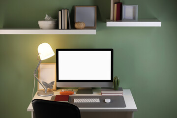 Stylish workplace with computer and grey mat on desk in office