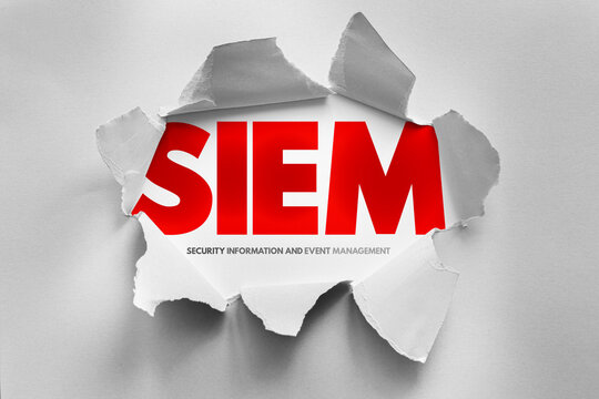 Acronym SIEM strikingly displayed through torn paper, revealing Security Information and Event Management - a vital cybersecurity system for monitoring and analyzing threats
