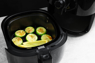 Air fryer basket with grilled vegetables on grey table, closeup