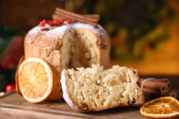 Christmas food. Delicious Panettone cake and festive decor on wooden table against background with blurred lights, closeup