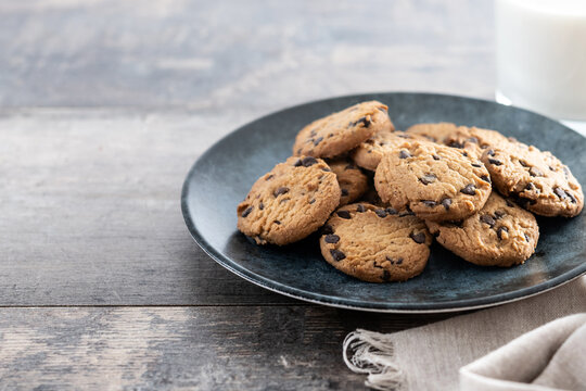 Chocolate chip cookies and milk for breakfast on wooden table. Copy space - Powered by Adobe