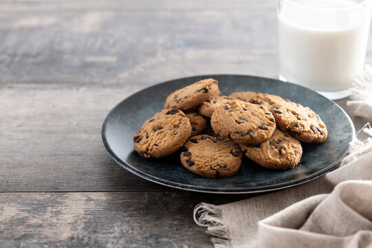 Chocolate chip cookies and milk for breakfast on wooden table. Copy space - Powered by Adobe