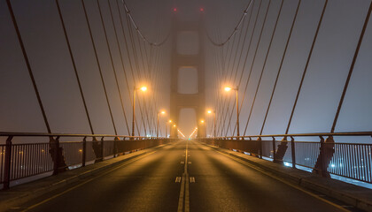 Foggy nighttime view of the Golden Gate Bridge with illuminated streetlights on a dark road