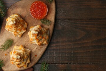 Christmas trees made with puff pastry, red caviar and festive decor on wooden table, flat lay. Space for text