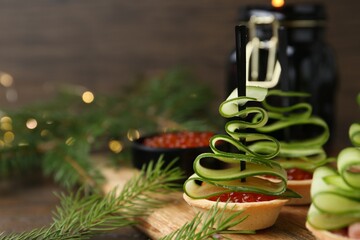 Christmas trees made with cucumber, red caviar and festive decor on table, closeup