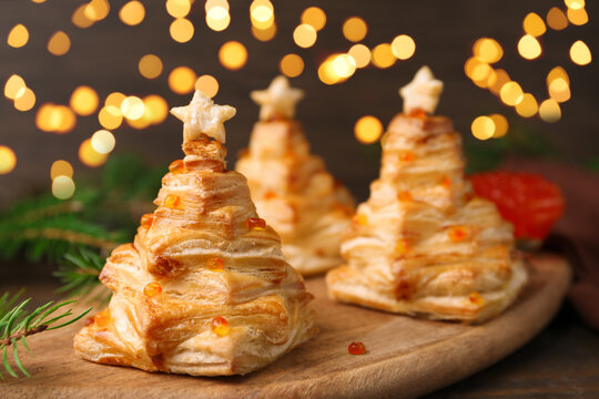 Christmas trees made with puff pastry, red caviar and festive decor on table, closeup