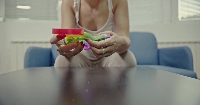Close-up of a person's hands engaging with a vibrant, heart-shaped Pop It fidget toy. The rhythmic popping creates calming, audible sounds, perfect for stress relief and relaxation.