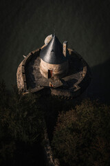Aerial view of historic round stone turret with conical roof and finial on castle wall at sunset © PIC by Femke