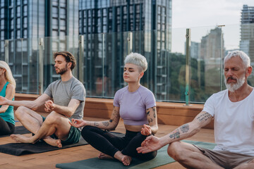 Serene people in activewear practising yoga on hotel rooftop terrace. Meditation together during outdoor class
