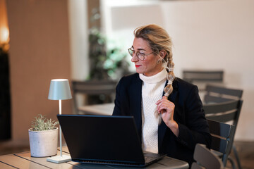 Confident businesswoman typing on laptop in evening office with calm focus and modern professional...