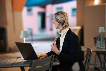 Elegant businesswoman with laptop working late in evening office focused on professional success...