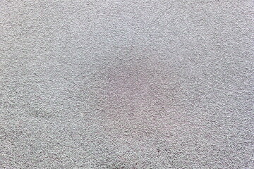Close-up view of a textured surface showing subtle color variations in gray and pink tones typical of smooth concrete or asphalt during daylight