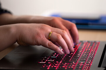 Close-up of a businesswoman working late typing on a blue backlight, backlit on laptop keypad.Anonymity on the Internet can provide benefits in terms of privacy and freedom of expression