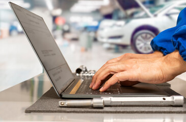 Close-up of hands of manager at the auto repair shop planning operations using laptop