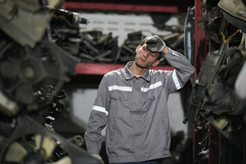 White man technician checking used car damaged engine block at scrap yard warehouse recycle area part. Maintenance engineer inspecting rust oily auto motor old spare part in junkyard for reuse service