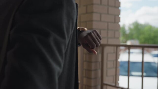 Close view highlights man in thick suit jacket, crisp button row and metal wristwatch, sleeve edge grazing polished case, tailored fabric texture and clean lines conveying business elegance mood