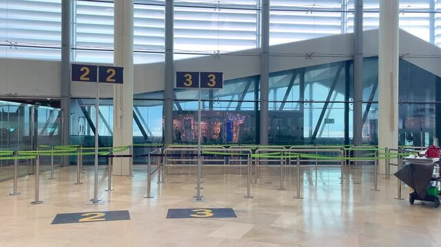 Young man with a backpack walking alone through a modern and empty airport terminal, heading towards the boarding gate for his summer vacation flight in Spain, representing solo travel concept.