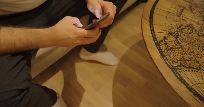 A smartphone slips from a man&rsquo;s hands and hits the floor in slow motion. The device remains functional, showing a realistic everyday accident at home.
