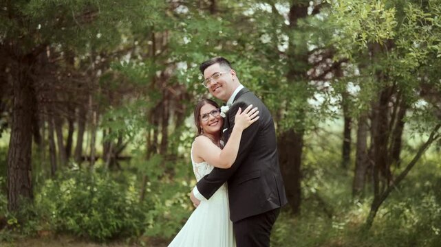 Slow-motion handheld shot as mixed couple hug and pose outside, smiling