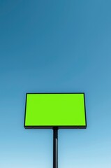 A modern, blank outdoor billboard featuring a vibrant green screen display, set against a clear, expansive blue sky. This versatile signage platform is perfectly positioned for seamless digital insert