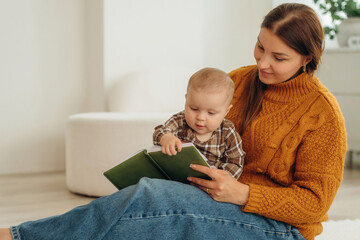 Interesting story reading. Happy mother with her baby daughter are at home together