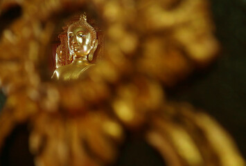 Closeup the Face of Gilded Buddha Image Reflecting on the Mirror of Teak Lacquered Pillar in Wat Phumin Temple, Nan Province, Thailand