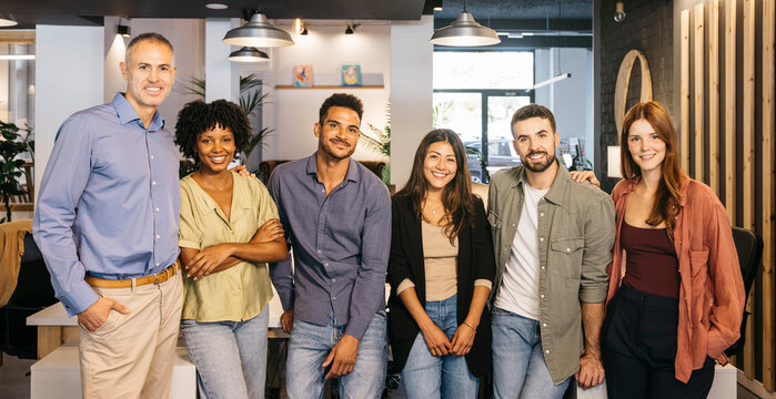 Group picture of diverse business team smiling at camera in modern office