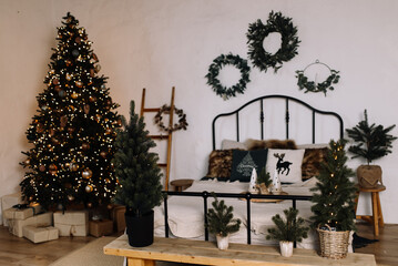 Christmas decor with modern accents: mini Christmas trees in pots, festive wreaths, and a stylish bed.