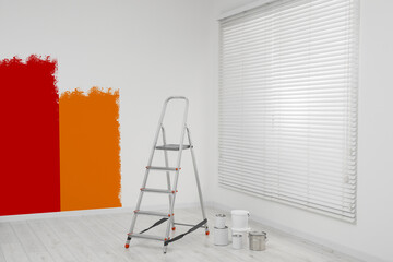 Choosing color for interior. Stepladder and paint on floor in room near wall partly painted in different shades