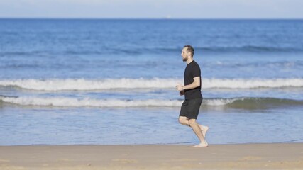 Barefoot athletic man jogging on the beach