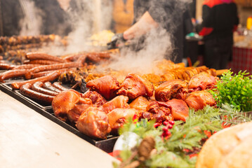 vendor fries meat and sausage on the grill in the city center at the Christmas market in Krakow Poland